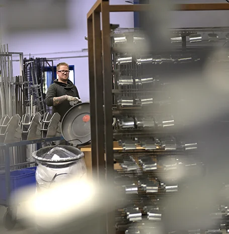 Mitarbeiter in der Produktionshalle von EWS neben Gestellen mit Metallbauteilen