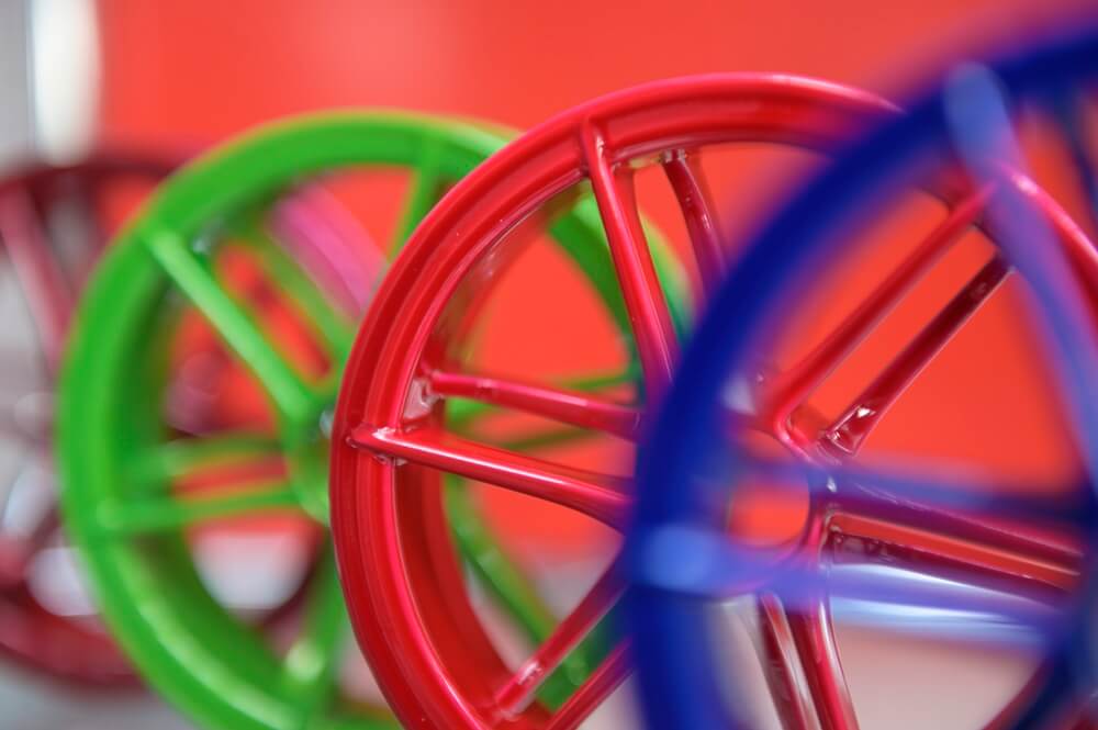 4 Bauteile, die in verschiedenen Farben pulverbeschichtet sind